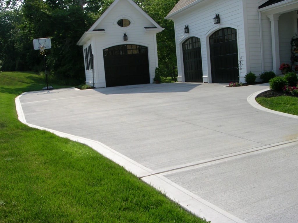 A spacious concrete driveway in Central Coast leads up to the white garage and frontyard of the main house